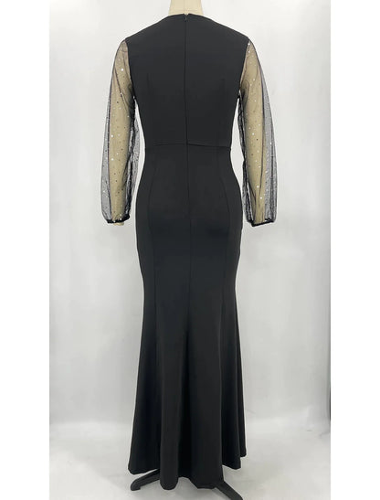 Side view of a woman in a sparkling long sleeve jewel neck mermaid trumpet formal dress.