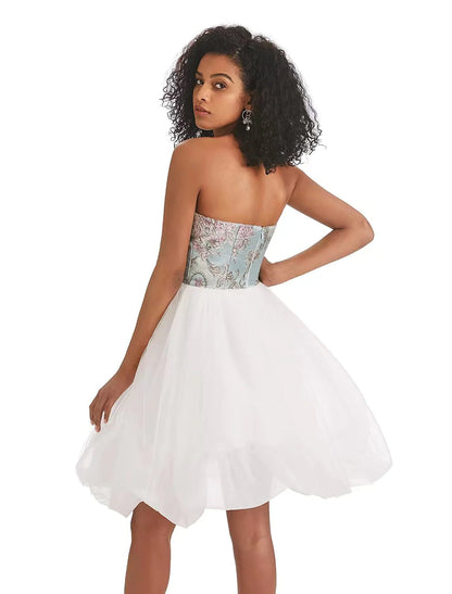 A woman showcasing the back detail of the A-line strapless color block tulle print dress.